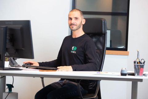 Membre de l'équipe TOTEM 3D à son bureau, en t-shirt aux couleurs de l'entreprise